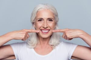 Older woman smiling and showing off perfect teeth.